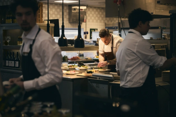 Kock som förbereder i köket och personal vid kassan